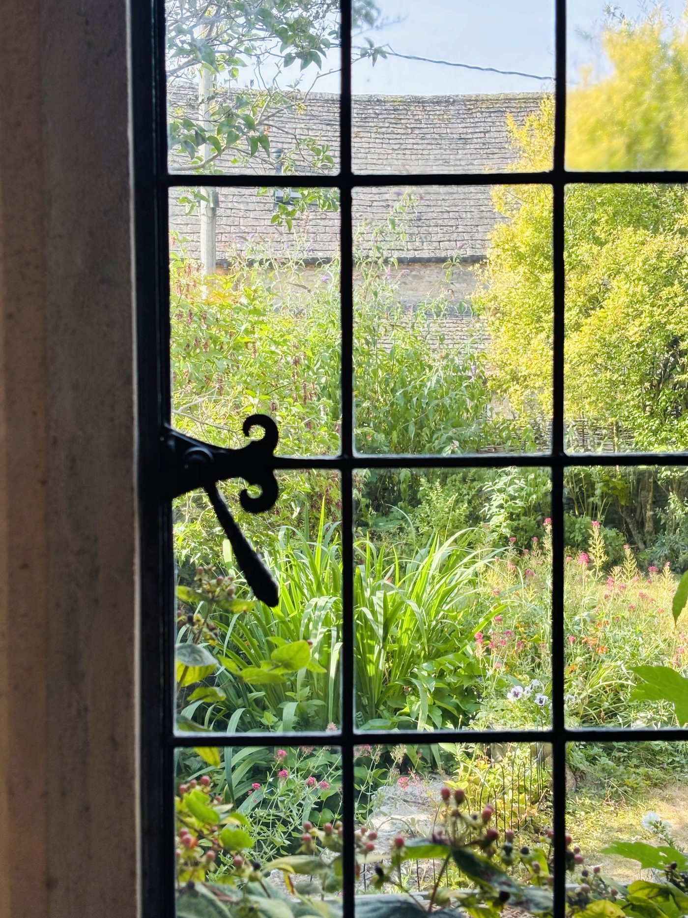 View through a leaded cottage window onto a Cotswold garden